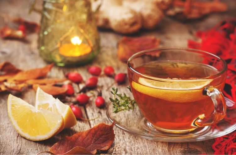 Un té in una tazza in vetro su una tavola adornata con i tipici frutti dell'autunno, rosa canina, melograno, castagne e foglie. e la tavola si colora come un dipinto 