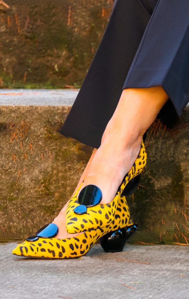 nell'imagine una paio di scarpe gialle stampa animalier divertenti e sbarazzine indossate con un tailleur classico diventano l'accessorio di spicco