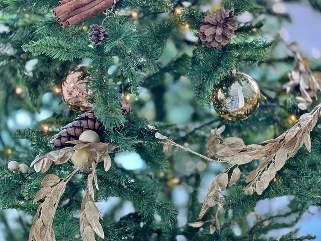 Nell'immagine sfere dorate, ghirlanda dorata per addobbare l'albero di Natale con pigne e cannella, un addobbo ispirato alla natura con un tocco glamour.