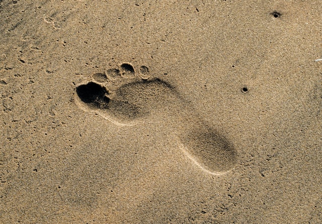 Un'orma nella sabbia di un piede. i piedi ci sorreggono e sono foindamentali per un portamento corretto che contribuiaca al benessere fisico. 